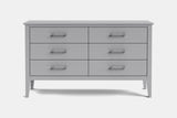 A light gray wooden dresser with six drawers and silver metal handles, shown against a plain light gray background.