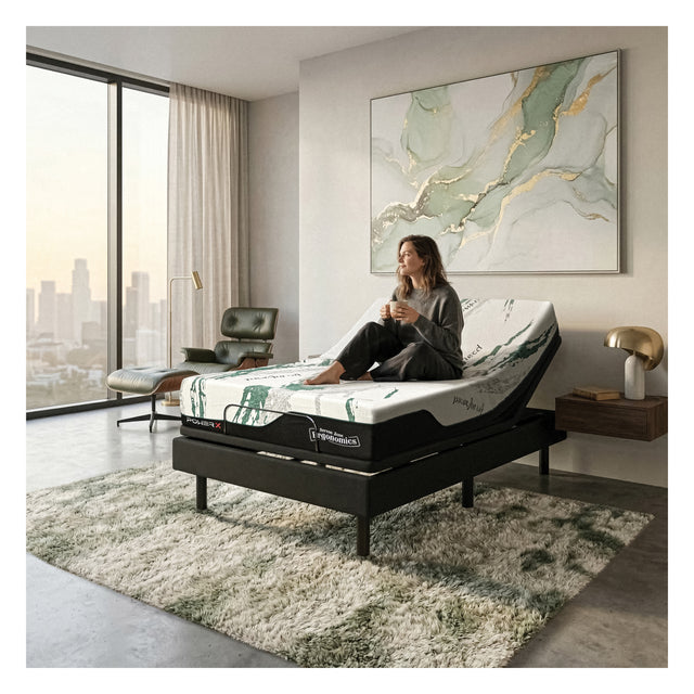 Woman sitting on adjustable Ergonomic mattress in a modern bedroom with large windows and a cityscape view.